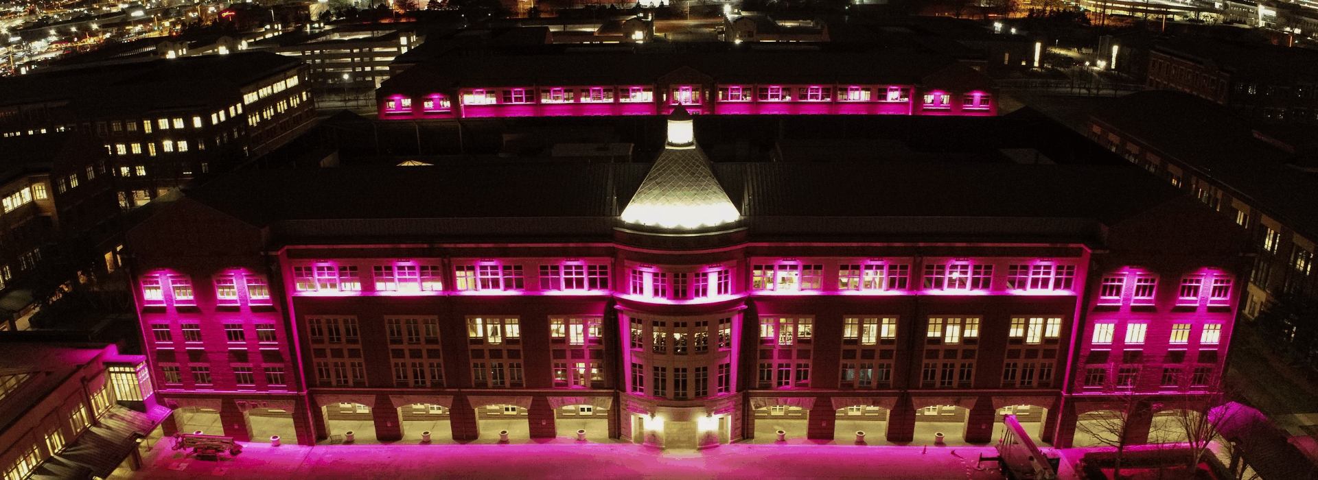 A night-time aerial view of the former Sprint campus in Kansas, now T-Mobile headquarters, lit up in magenta to signify the company’s branding.