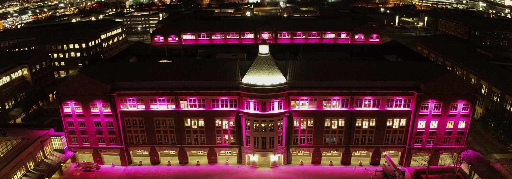 A night-time aerial view of the former Sprint campus in Kansas, now T-Mobile headquarters, lit up in magenta to signify the company’s branding.