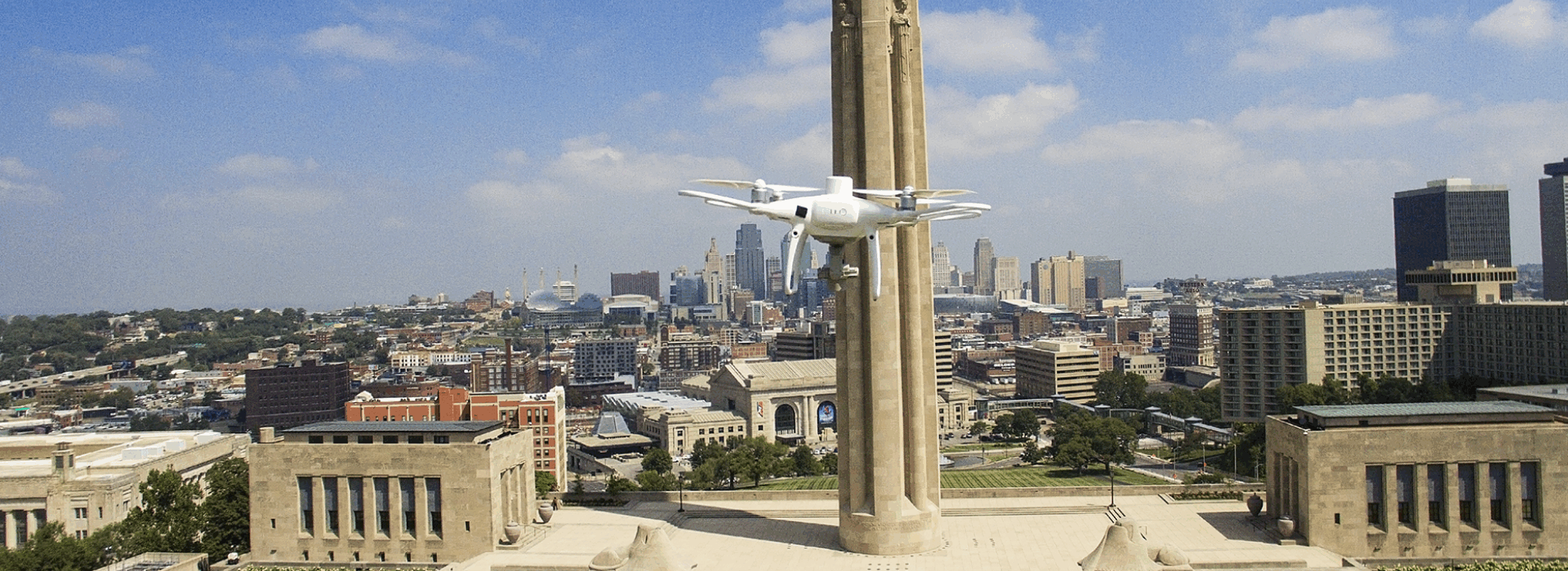 A drone hovering in front of the Liberty Memorial in Kansas City, with the downtown skyline in the background featuring various buildings and landmarks.